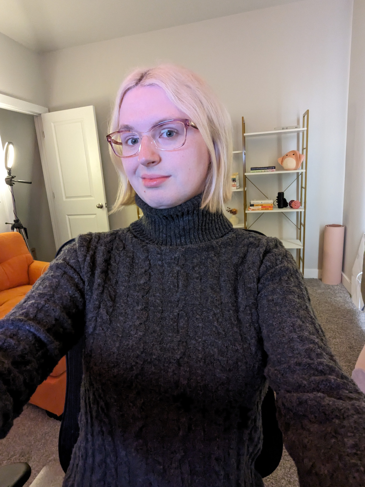 blonde woman sitting in office chair wearing a knit turtleneck sweater dress