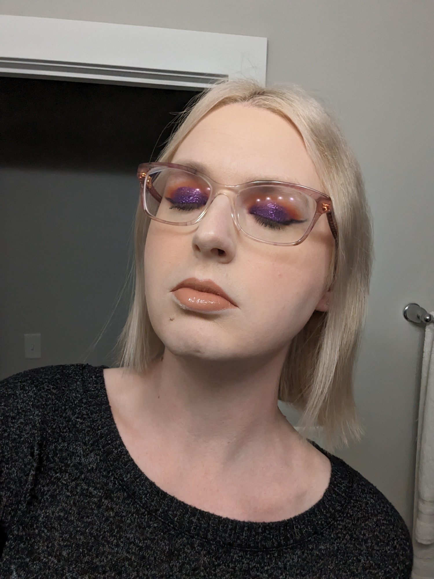 sky with her eyes closed and neutral expression to highlight her makeup—she has sunset-themed eyeshadow, orange blush, and a peach lipstick with gloss. she has slightly shorter than shoulder-length st