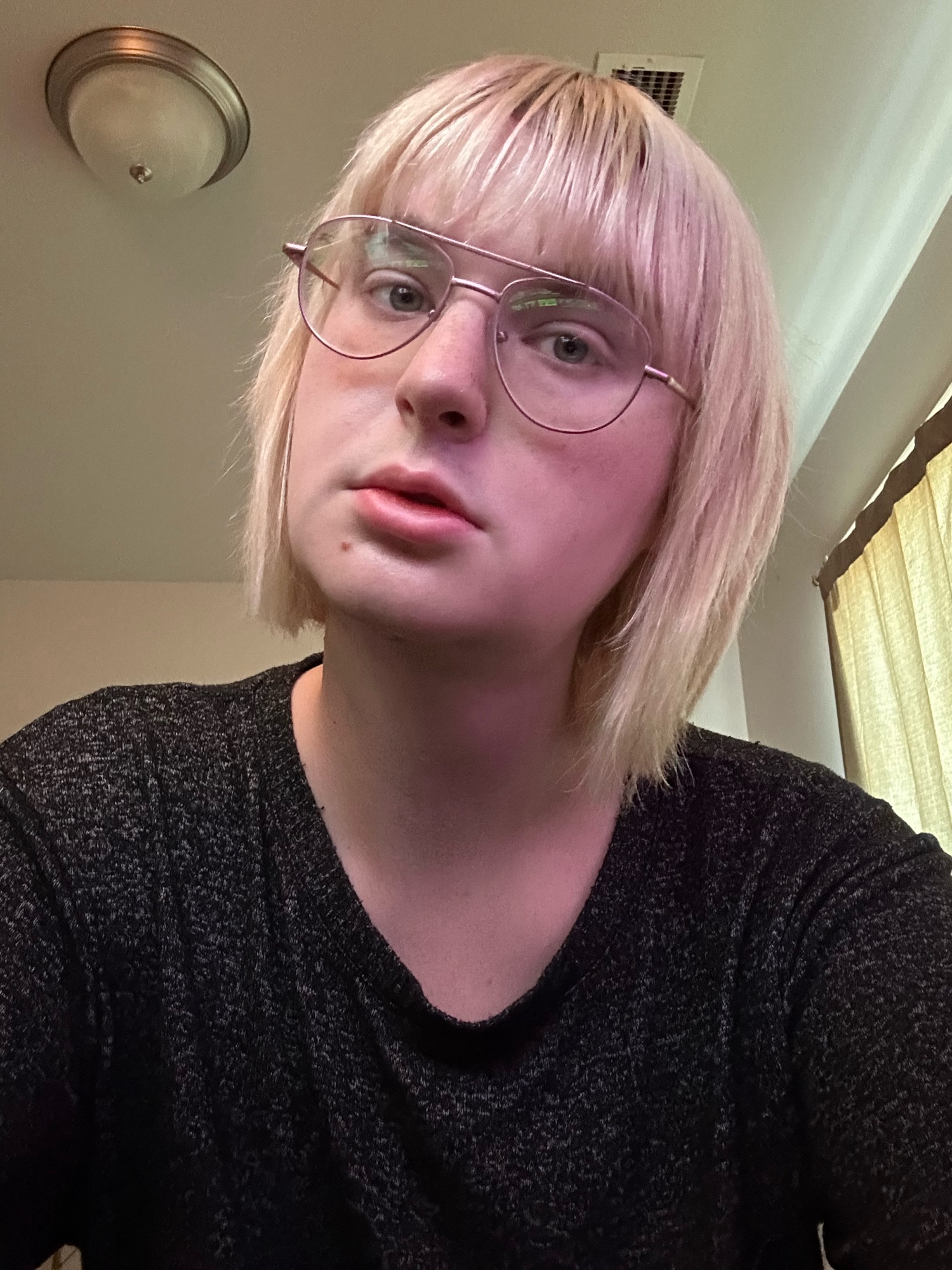 skylar, a blonde woman with bangs and short hair, taking a selfie with a neutral expression