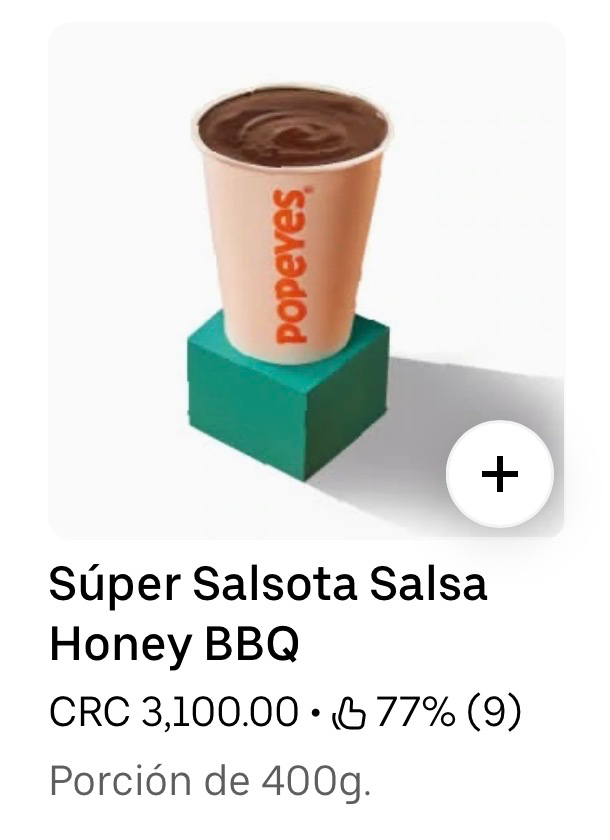 a screenshot from uber eats showing a 300g (14oz) cup full of Honey Barbeque sauce from Popeyes sitting on a green box with a harsh accent shadow. The text below reads: Súper Salsota Salsa Honey BBQ C