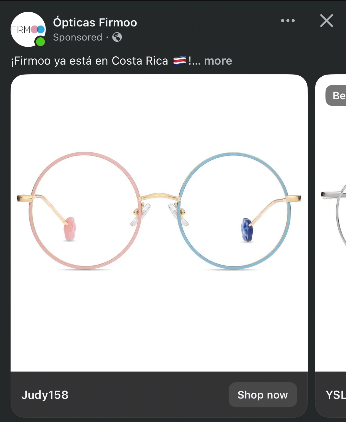 Screenshot of a sponsored Facebook post from Ópticas Firmoo. The ad copy reads "¡Firmoo ya está en Costa Rica 🇨🇷!" The product shown is a single pair of round eyeglass frames with gold metal temples and nose bridge, but with two different colored rims — the left lens is pink and the right is light blue, each with a matching colored nose pad. The frame style is labeled "Judy158." A "Shop now" button appears in the bottom right.